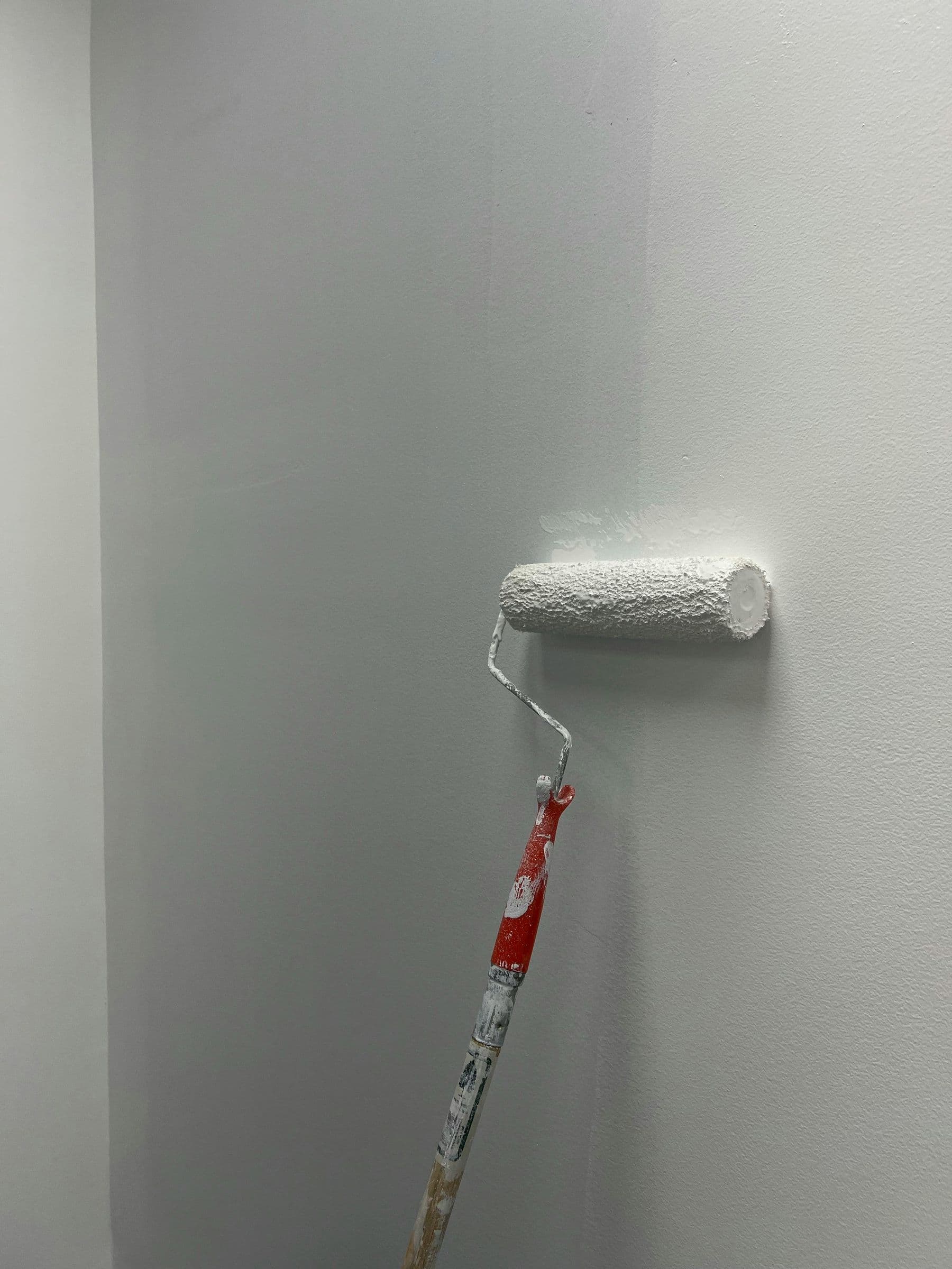Paint roller applying a fresh white coat to an interior wall
